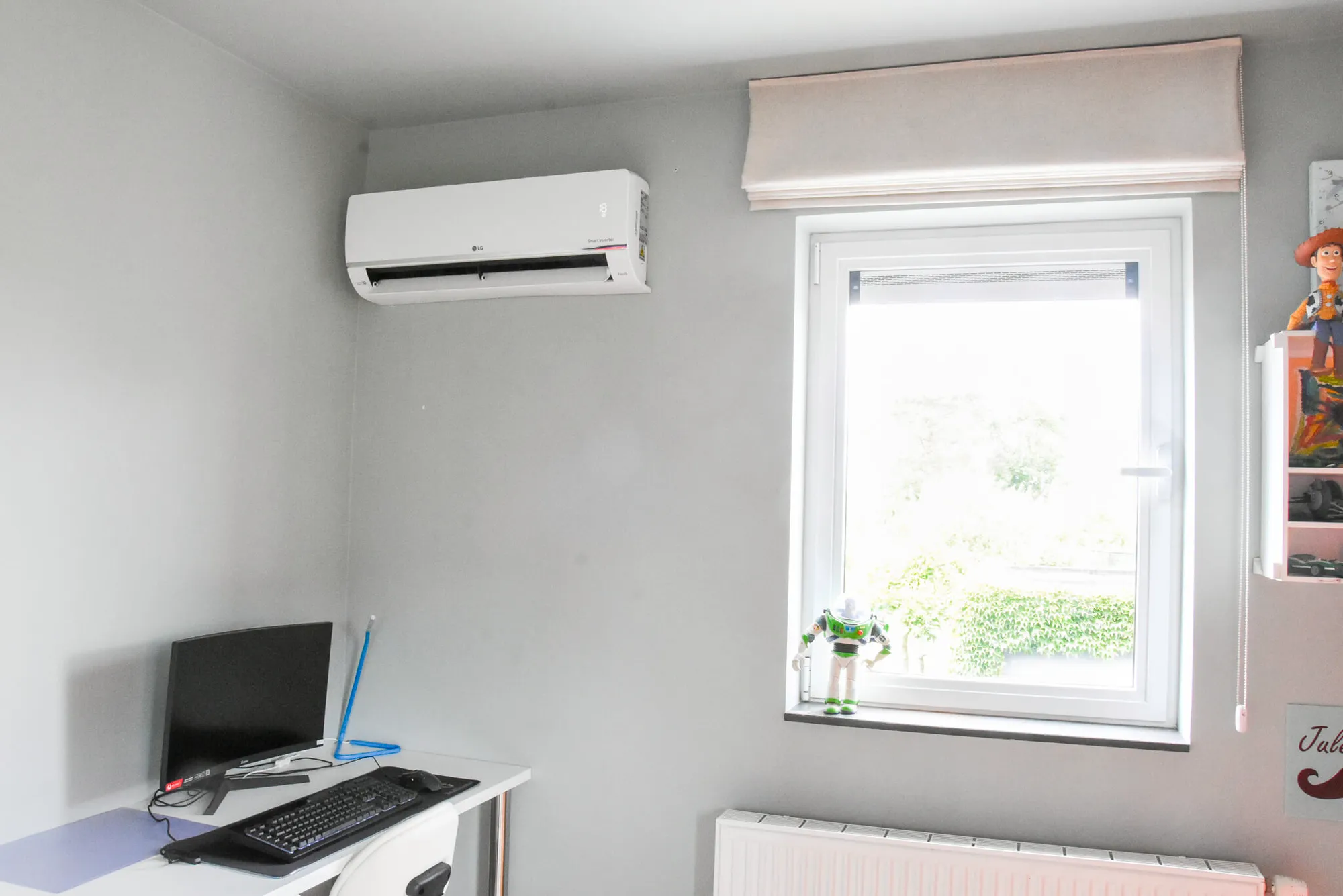 LG Smart Inverter airco geïnstalleerd in grijze kinderkamer met bureau en raam, energiezuinige oplossing van Energy Protect.