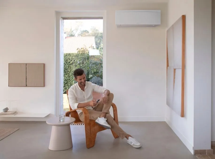 Man ontspant in een lichte woonkamer met een airco-binnenunit aan de muur