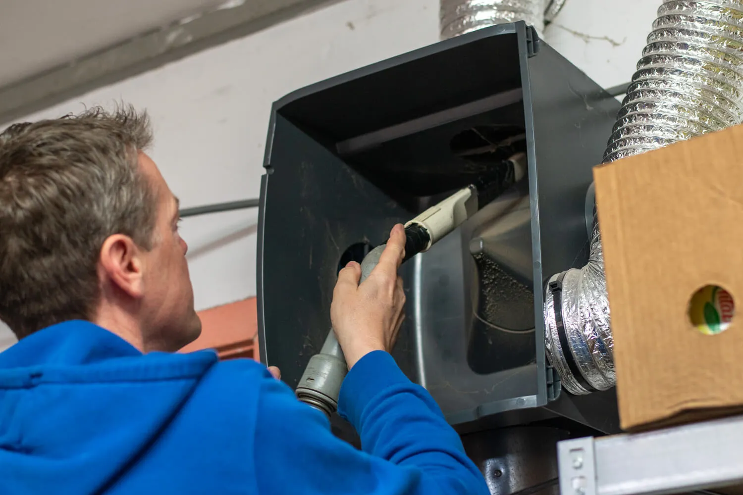 Technicus reinigt een ventilatie-unit met flexibele luchtkanalen tijdens onderhoud