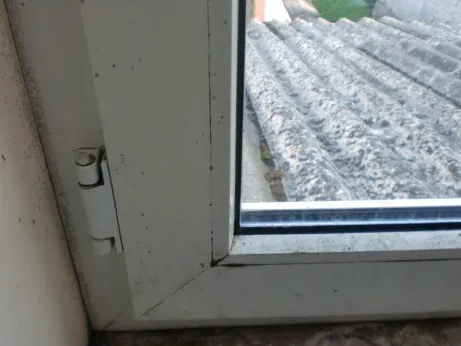 Zwarte schimmelstippen op een wit raamkozijn door condensatie, een geval voor vochtbestrijding