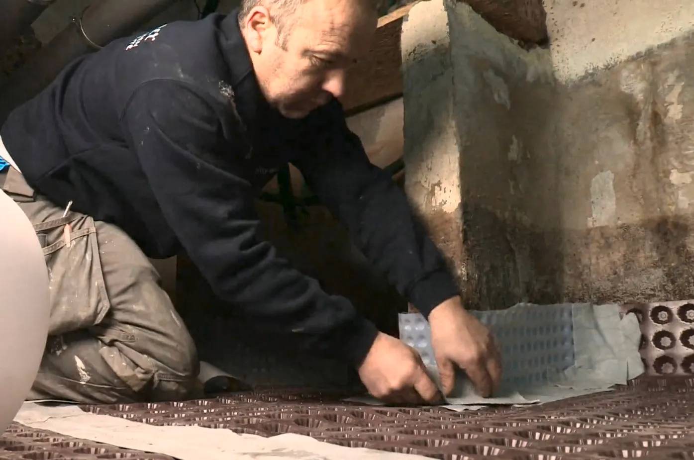 Aqua Protect vakman legt kelderdrainage aan langs vochtige betonnen muur