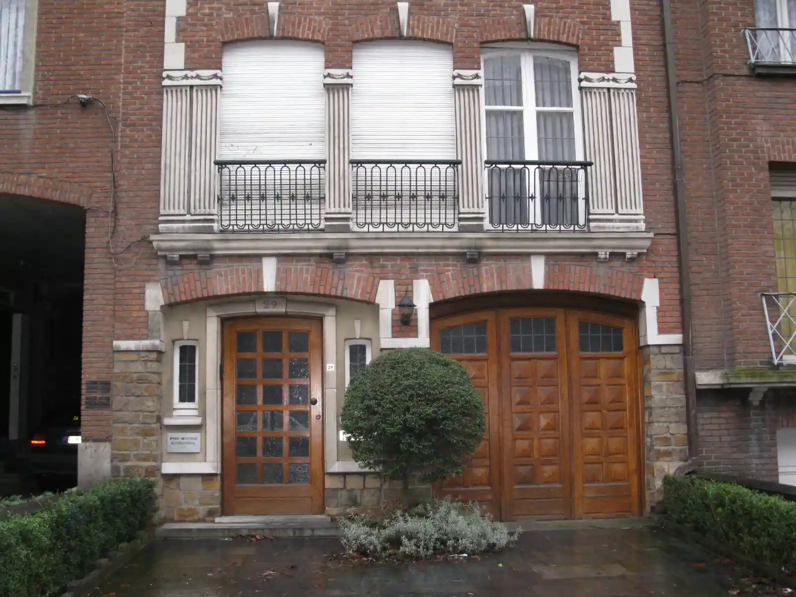 Bakstenen herenhuis met balkon, houten voordeur en garagepoort