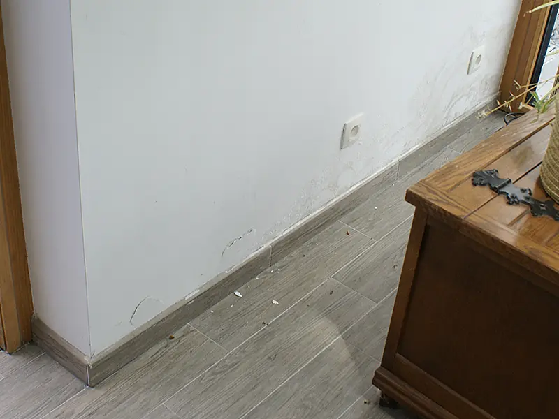 Binnenmuur met afbladderende verf en vochtvlekken bij de vloer, een geval voor vochtbestrijding