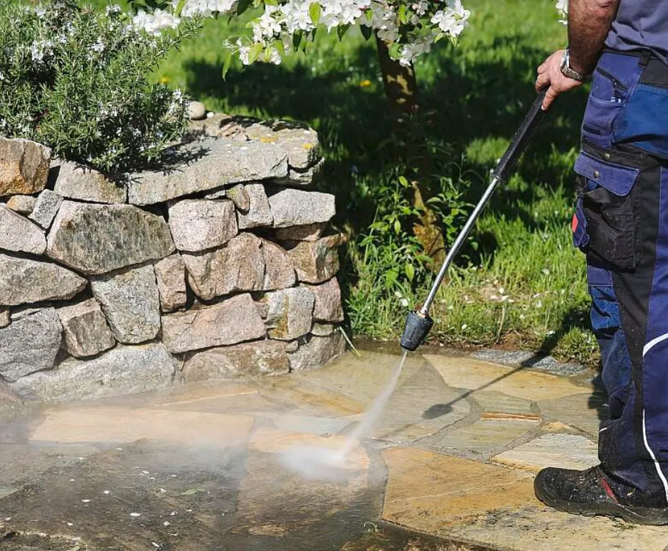 Reiniging van een natuurstenen terras met een hogedrukreiniger in een tuin
