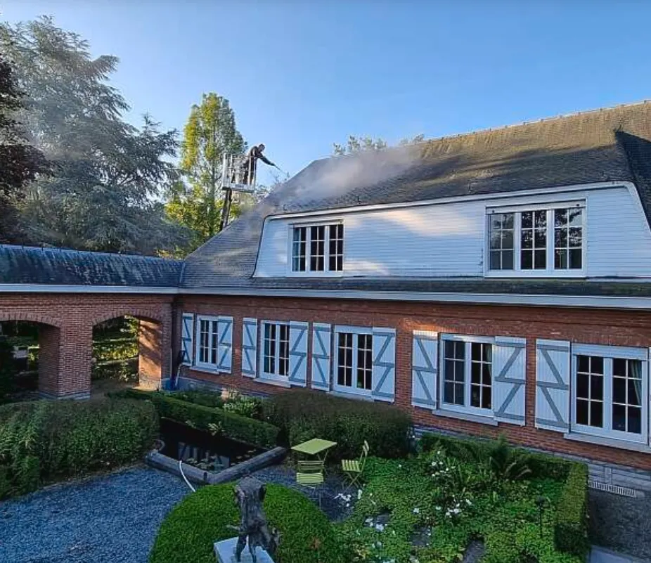 Hogedrukreiniging van een dak op een landelijk herenhuis tijdens ontmossing