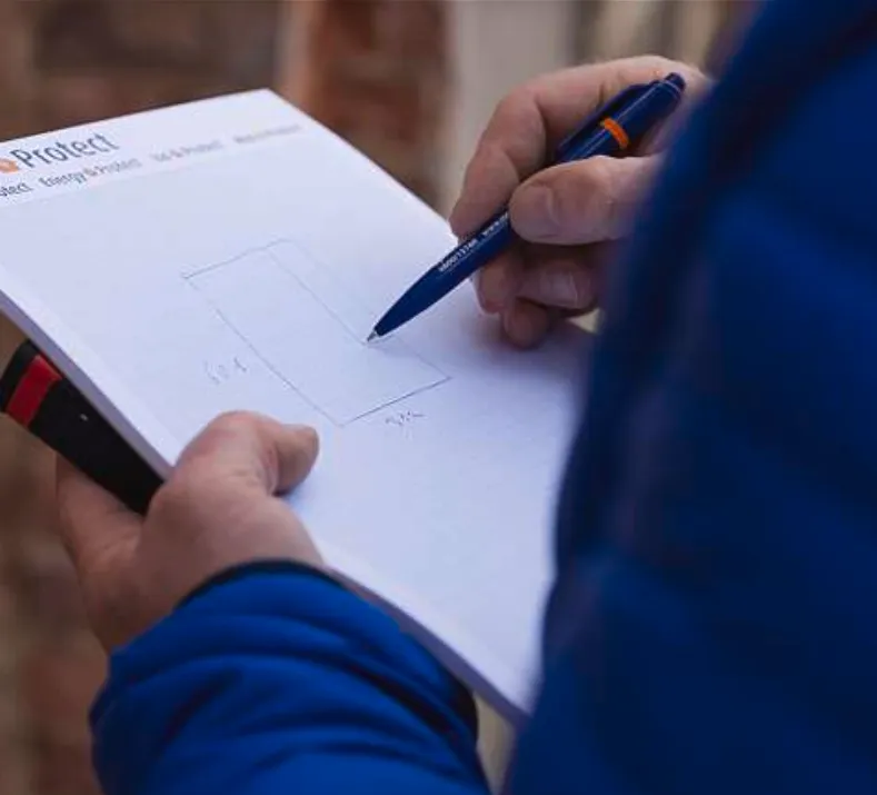 Adviseur in blauwe jas schetst een opmeting op een klembord aan een bakstenen gevel