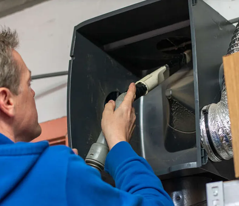 Vakman reinigt met een slang de binnenkant van een ventilatie-unit met flexibele luchtkanalen