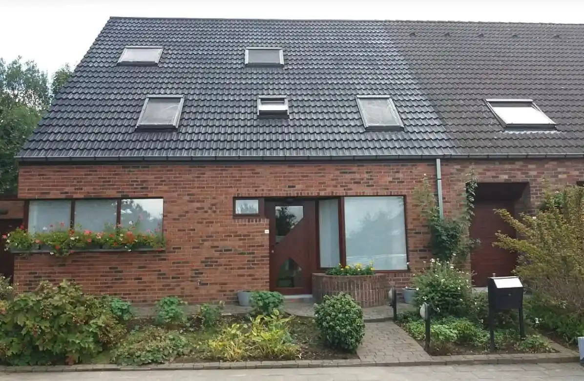 Bakstenen woning met pannendak en meerdere dakvensters, met voortuin