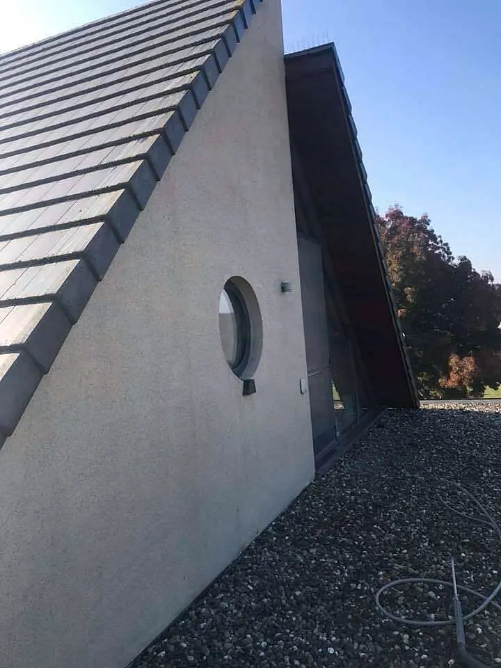 Moderne woning met lichtgrijze gepleisterde gevel, rond zijraam en pannendak