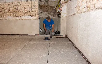 Arbeider plaatst nieuwe vloerplaten in een kelder, vóór kelderdichting