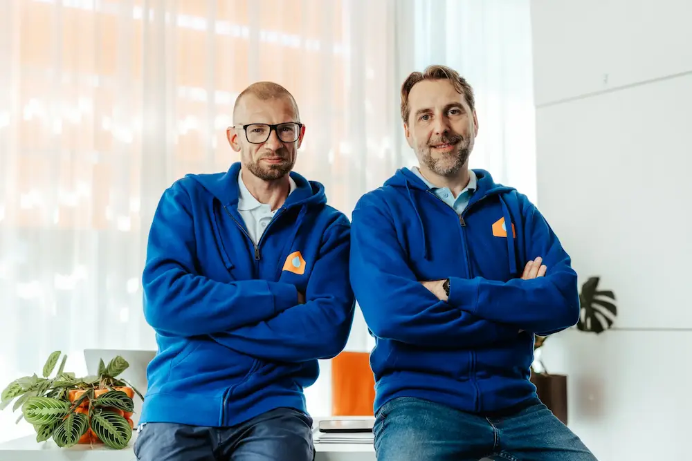 Twee vochtexperten van Aqua Protect in blauwe bedrijfshoodie in een licht kantoor