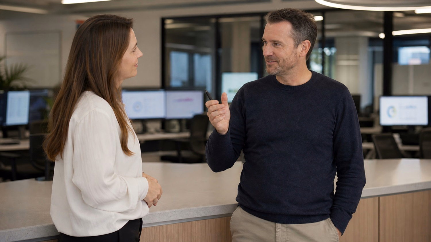 Two Caucasian colleagues in their early 40s, standing and engaged in a discussio