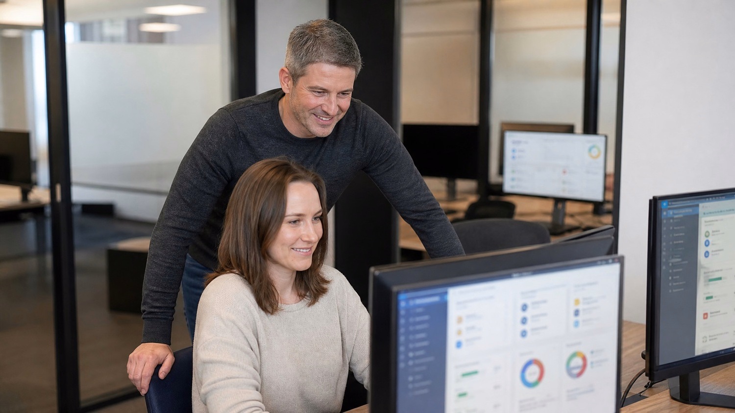 Man behind woman, both view cybersecurity training on monitor