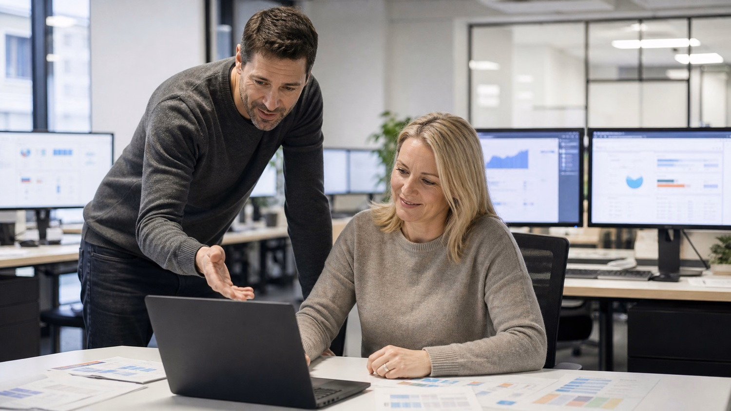 Man explains laptop screen to colleague, business strategy