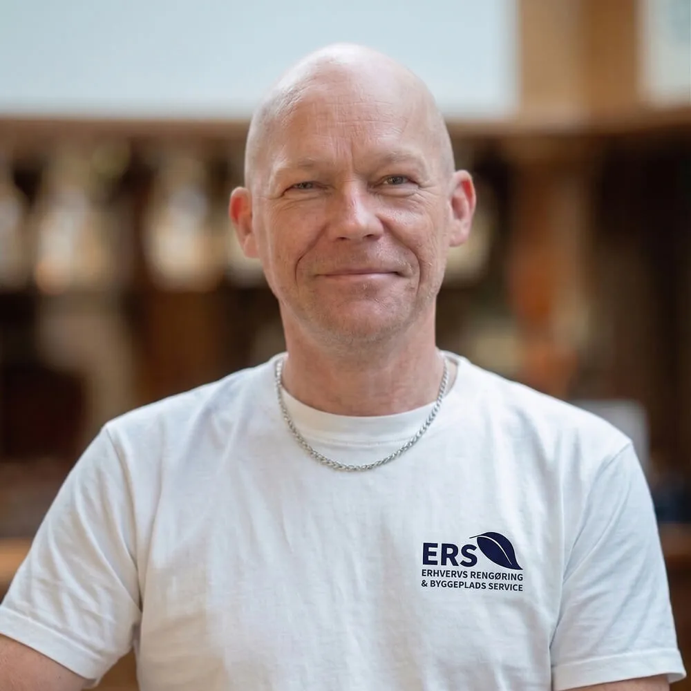 Ejer af ERS iført hvid T-shirt med ERS logo og smilende ind i kamera.