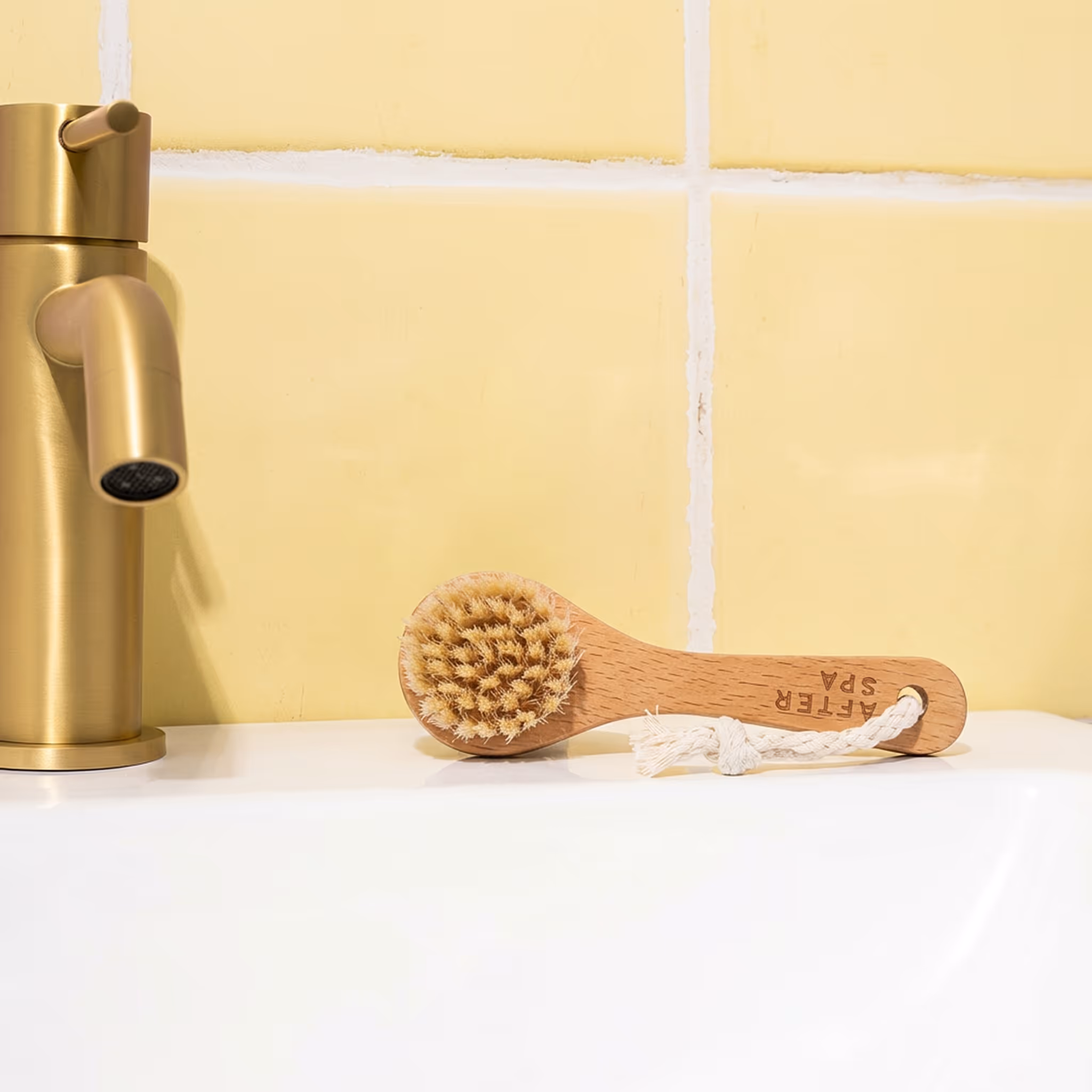 Facial dry brush with wooden handle on bathroom sink near faucet