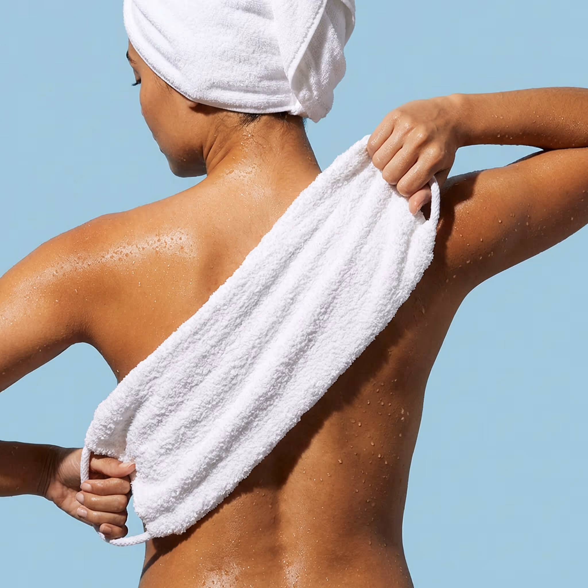 Woman using After Spa Exfoliating Wash Cloth across back for body exfoliation and cleansing.
