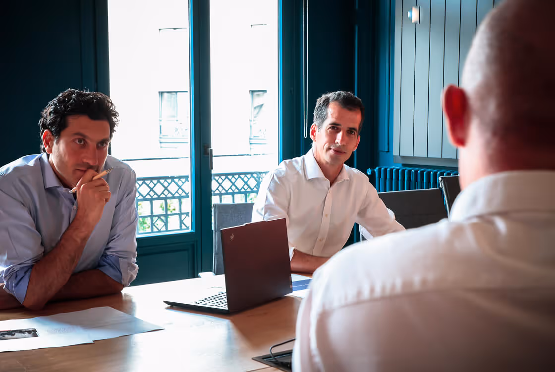 Trois hommes discutant autour d'un ordinateur