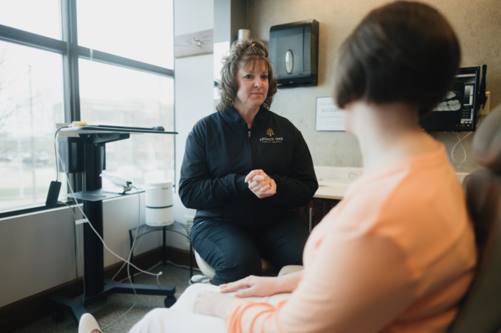 Dentist consulting with patient by large window during appointment