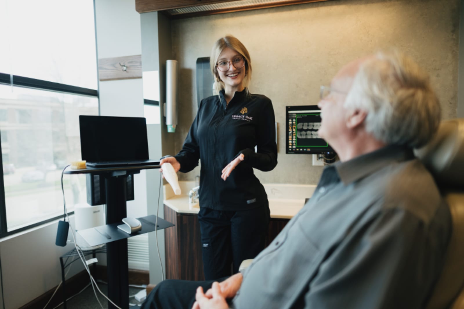 Female dentist in dark uniform presenting dental education materials to a patient