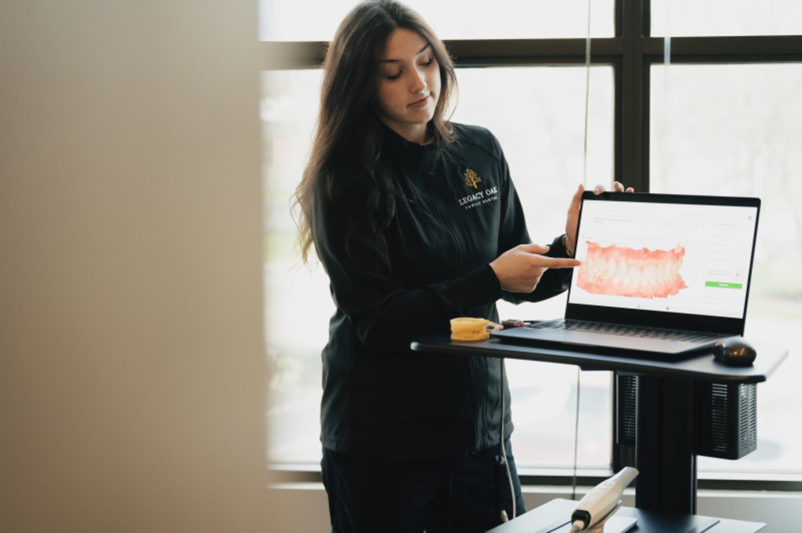 Dentist showing digital smile design on computer screen to female patient