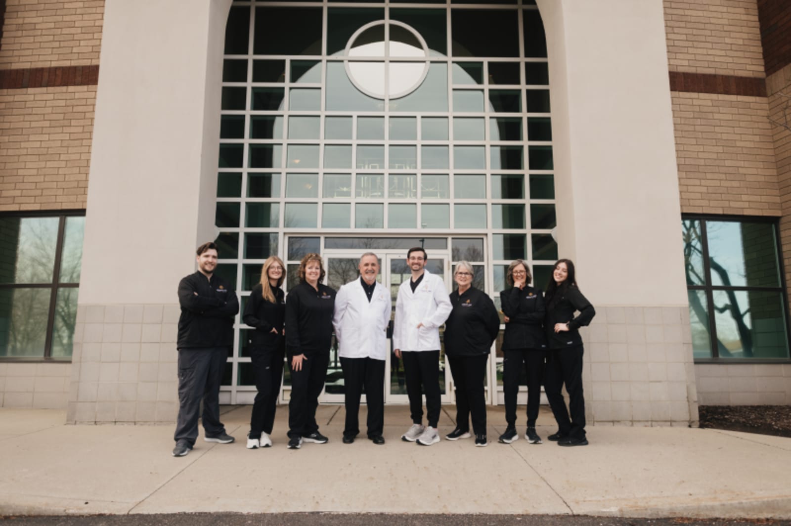 Team of dental professionals standing together in front of practice building entrance
