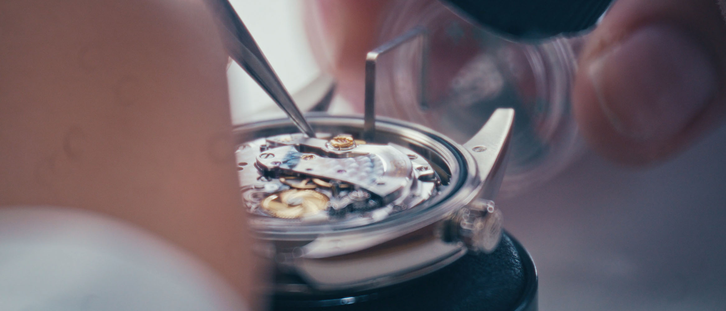 Close-up of a watchmaker assembling the intricate inner mechanism of a wristwatch with small tools.