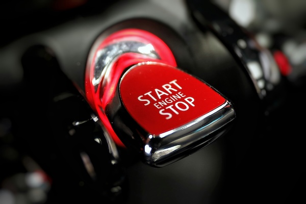 Close-up of a red car start engine stop button with chrome edges.