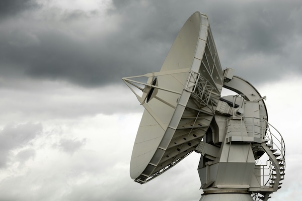 Large white satellite dish signal receiver under a cloudy gray sky.