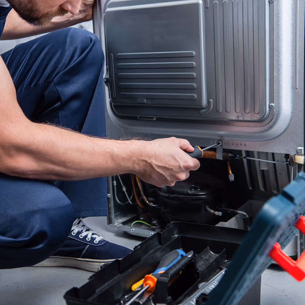 D&D technician working on an appliance with hand tools, representing our appliance parts counter and repair service