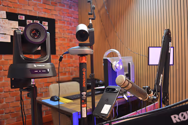 Professional video and audio equipment setup including cameras, microphone, and computer in a recording studio.