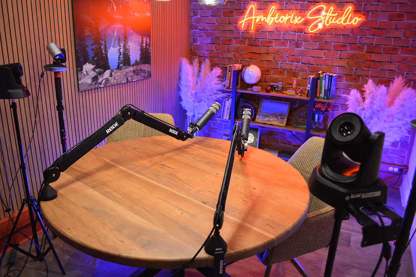 Workspace with a desktop monitor showing a night sky with stars and a green tent, a keyboard, mouse, and microphone on a wooden desk.