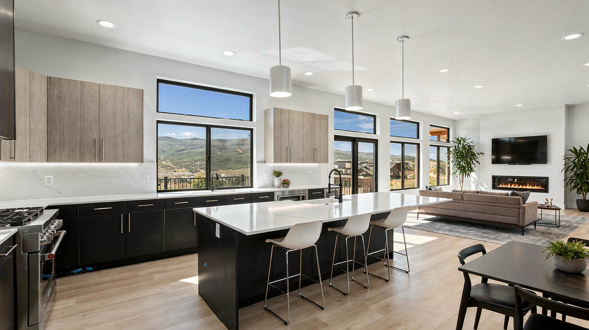 Sunlight open-plan kitchen and great room with dark lower cabinets, white quartz island with modern barstools, cylinder pendants, clerestory windows with mountain views, and linear fireplace
