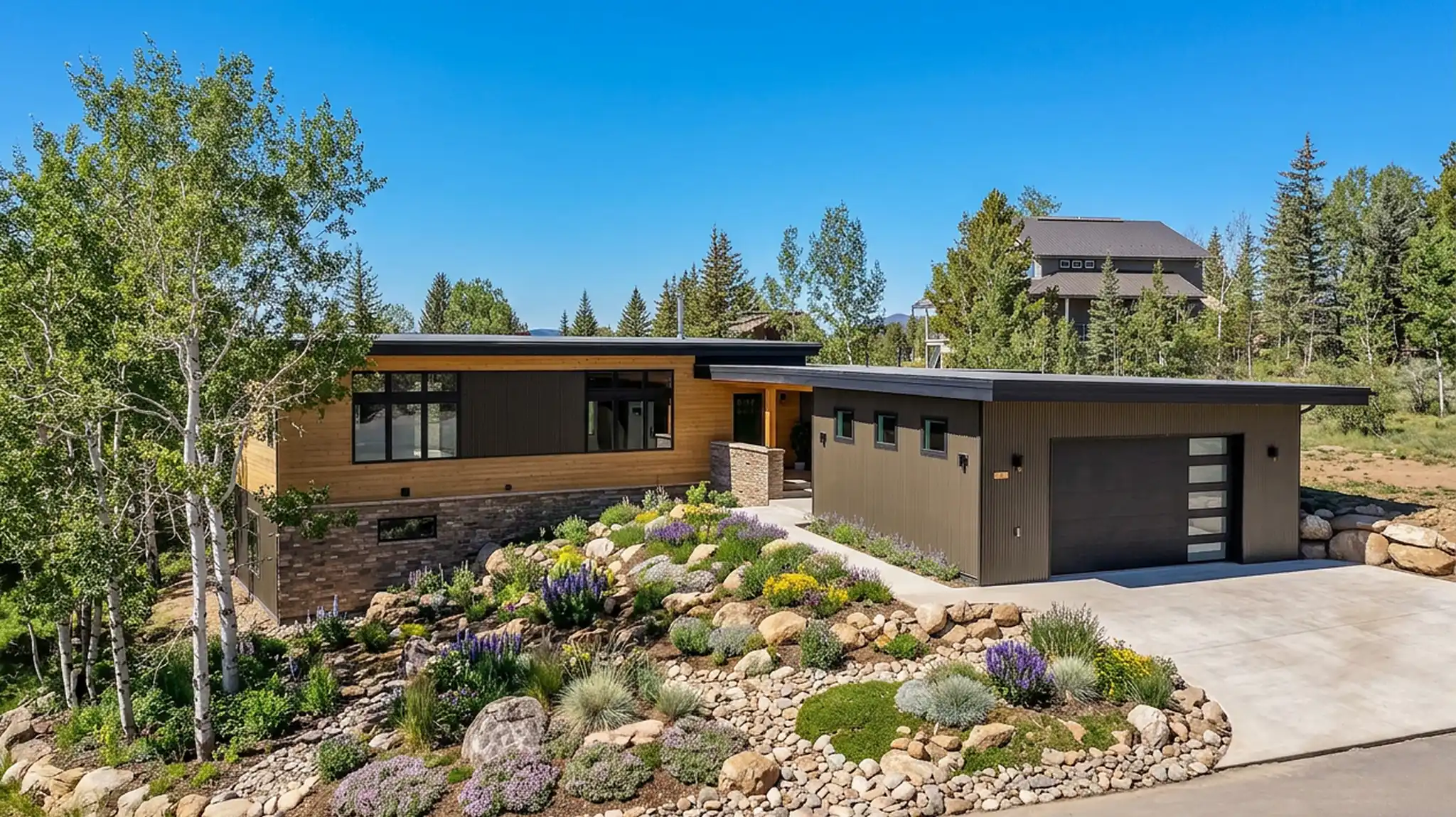 Telemark front exterior with cedar and dark trim siding, flat shed roof, attached garage with contemporary door, and colorful xeriscape landscaping with boulders
