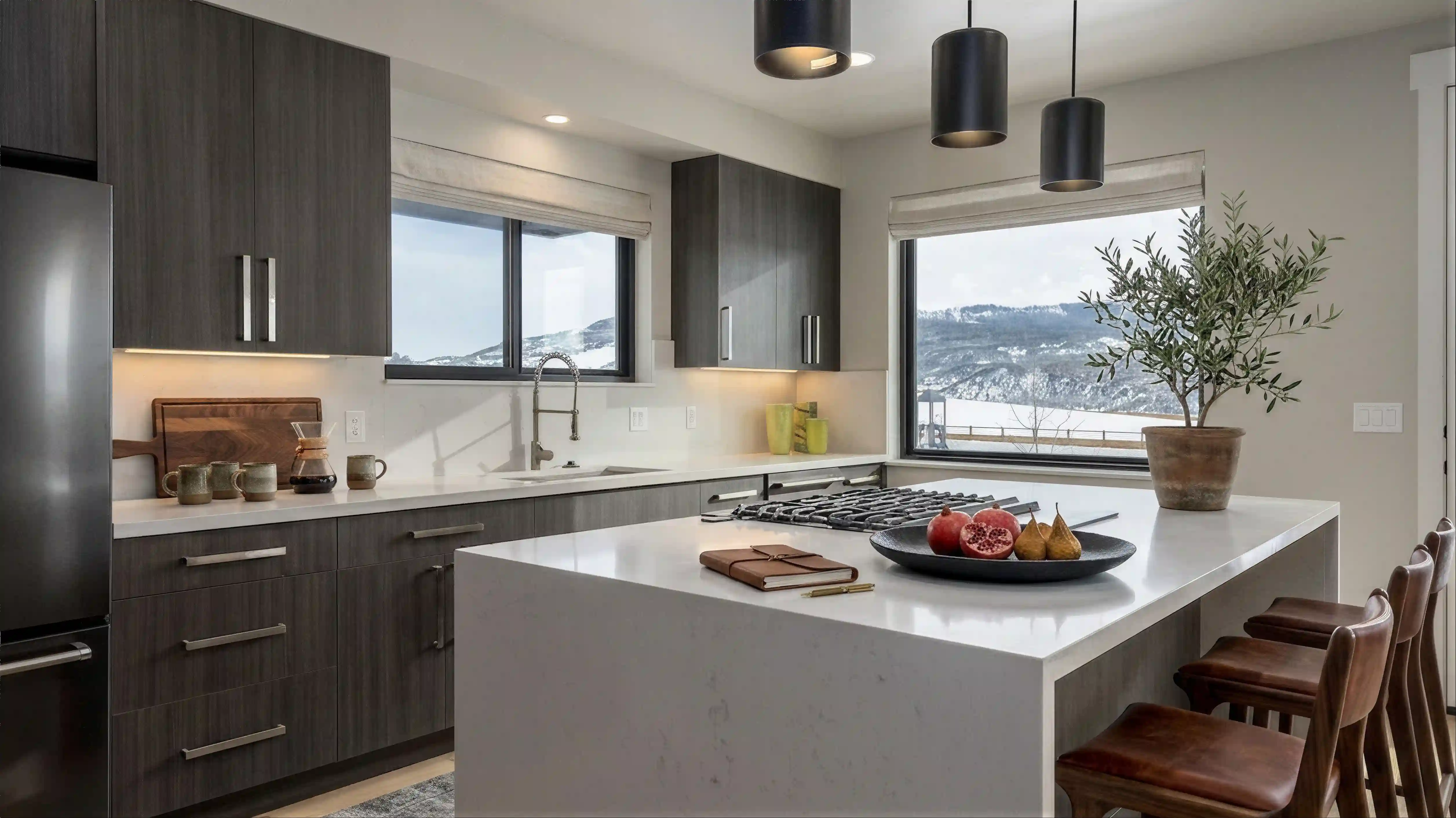 Twilight kitchen with dark wood cabinetry, white quartz island and countertops, pendant lighting, and mountain views through large windows