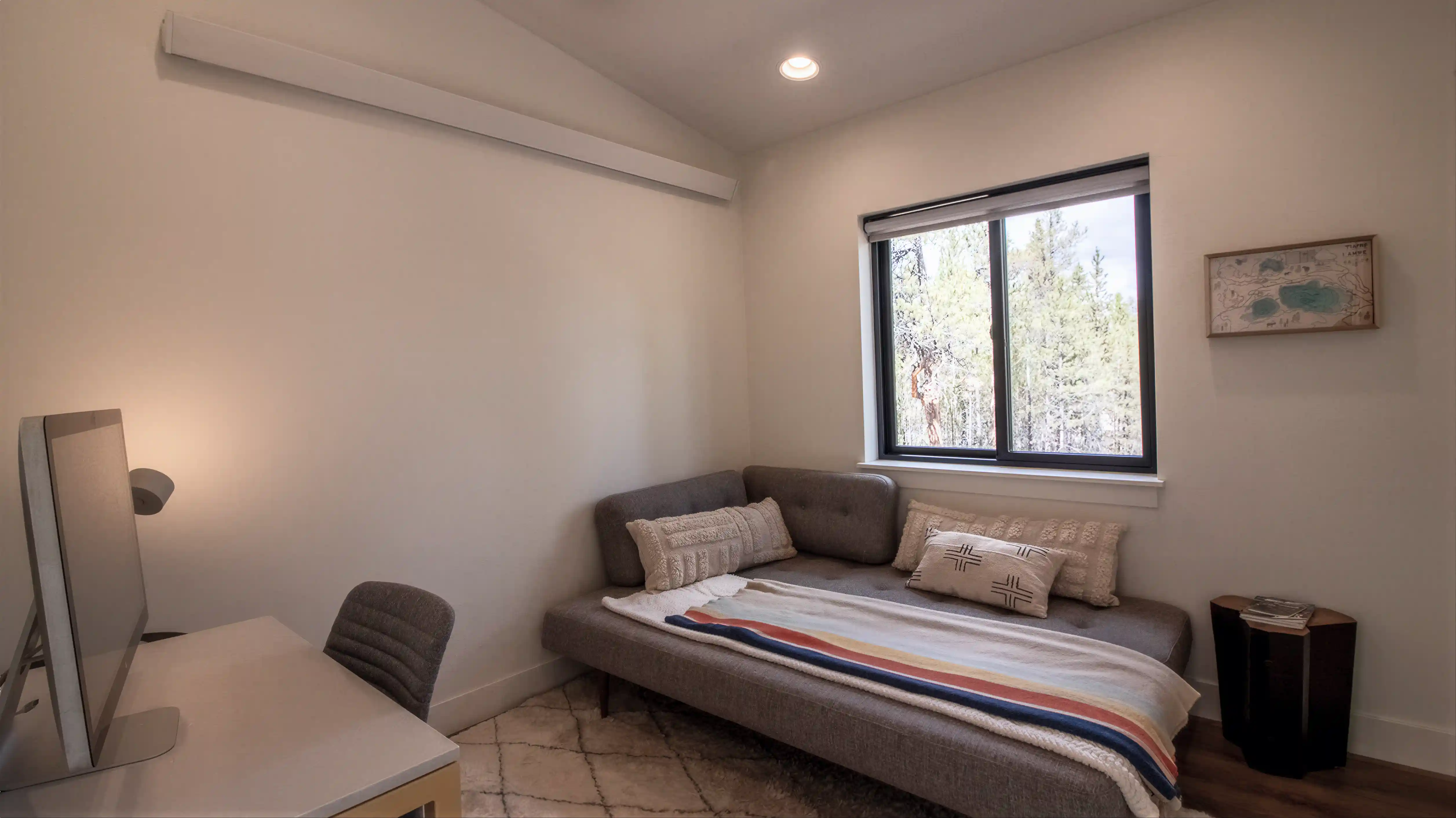 Hideaway flex room with daybed sofa, desk, window overlooking pine trees, and wall-mounted mini-split unit