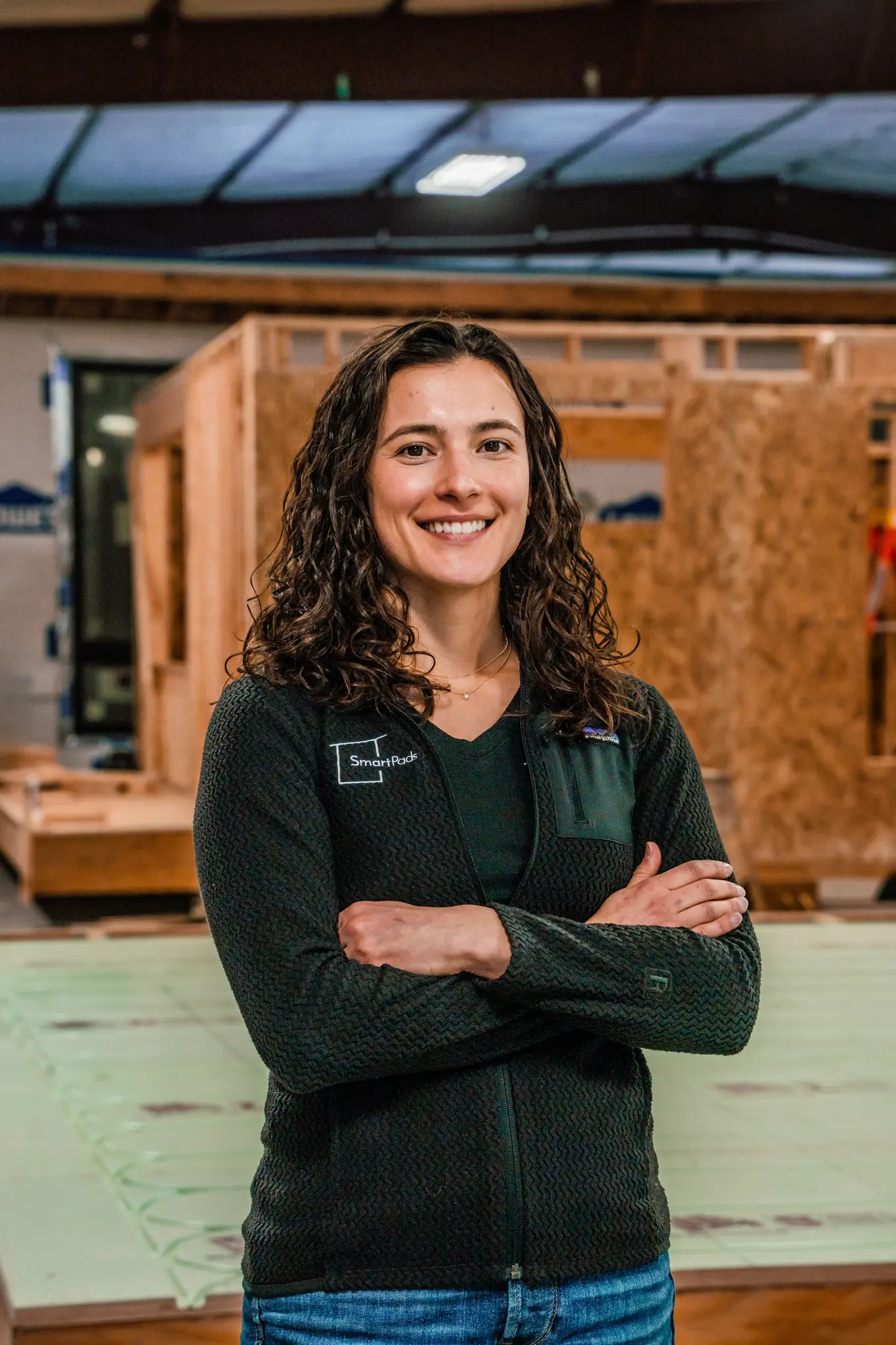 Smartpads team member smiling with arms crossed wearing a Smartpads vest in the manufacturing facility