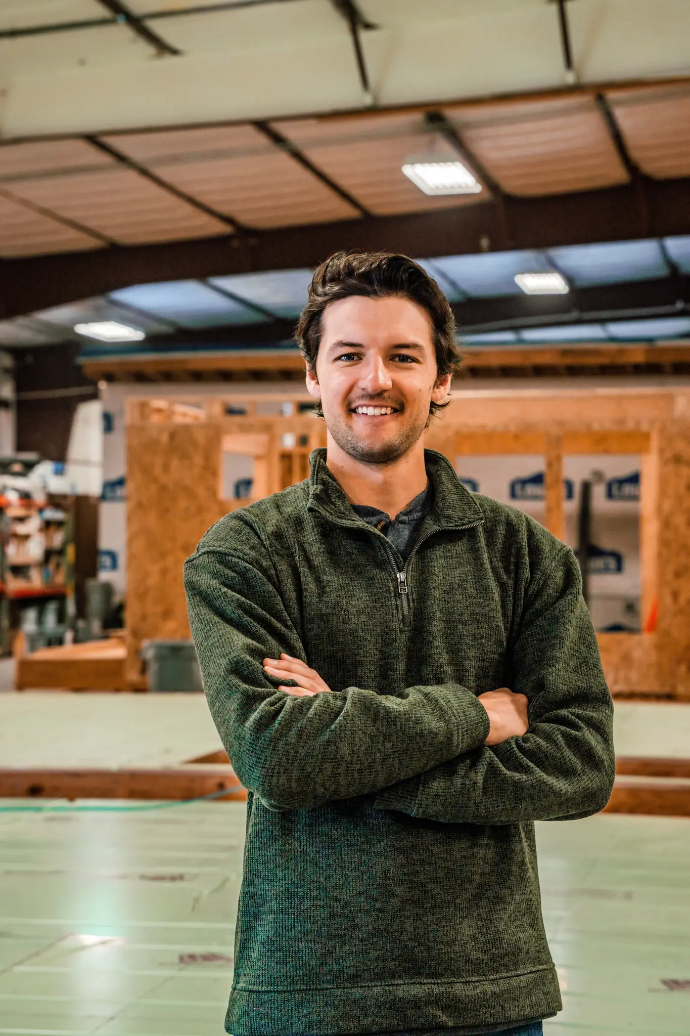 Smartpads team member in green pullover smiling inside the modular home factory
