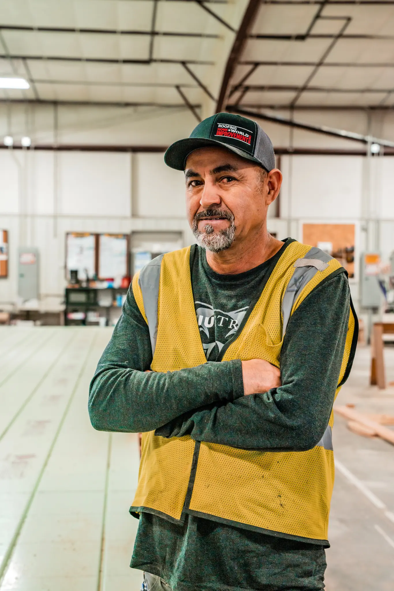 Experienced Smartpads worker in yellow safety vest and cap in the modular home manufacturing facility