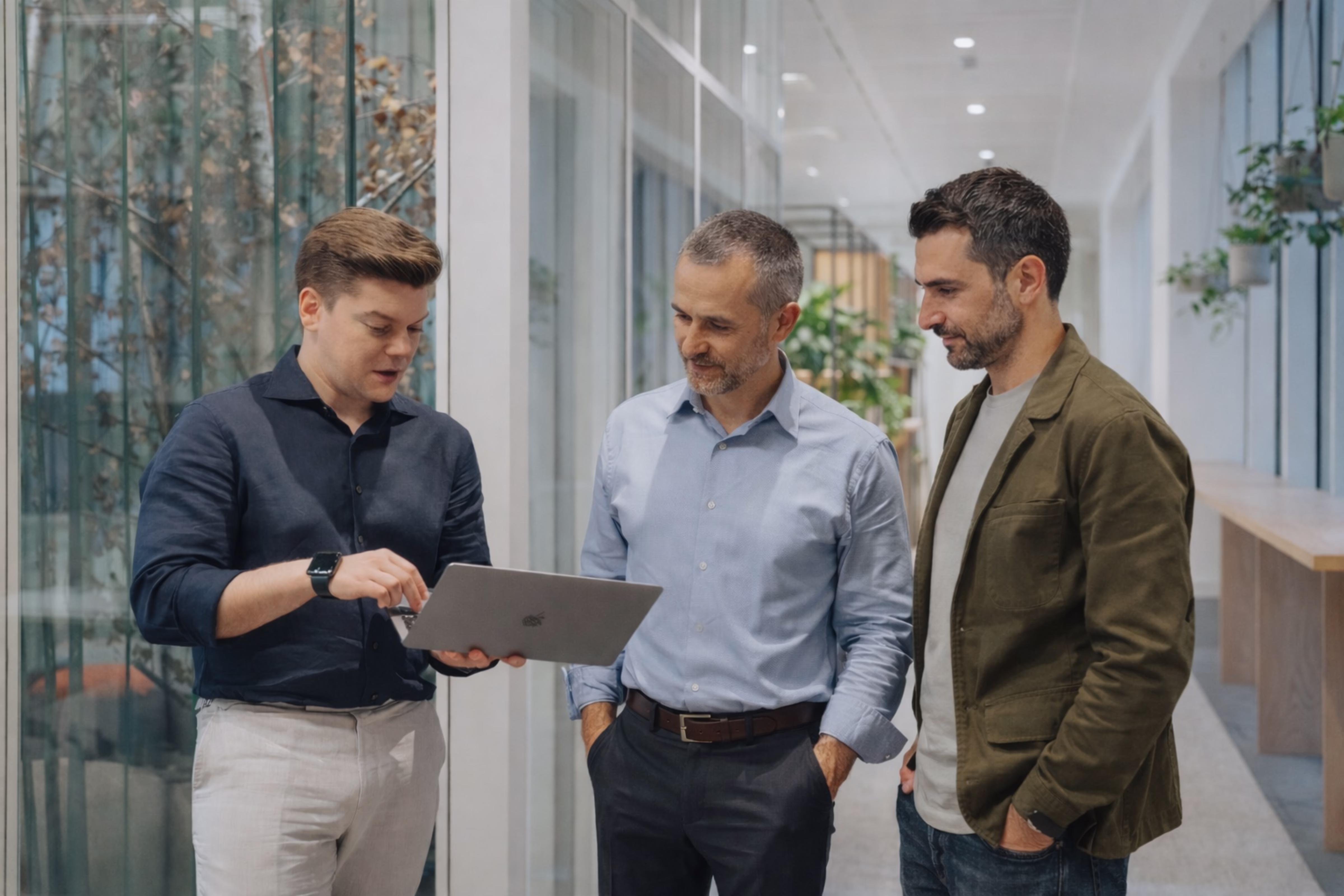 Robbie bespreekt pricing-inzichten met twee klanten in een kantoorgang