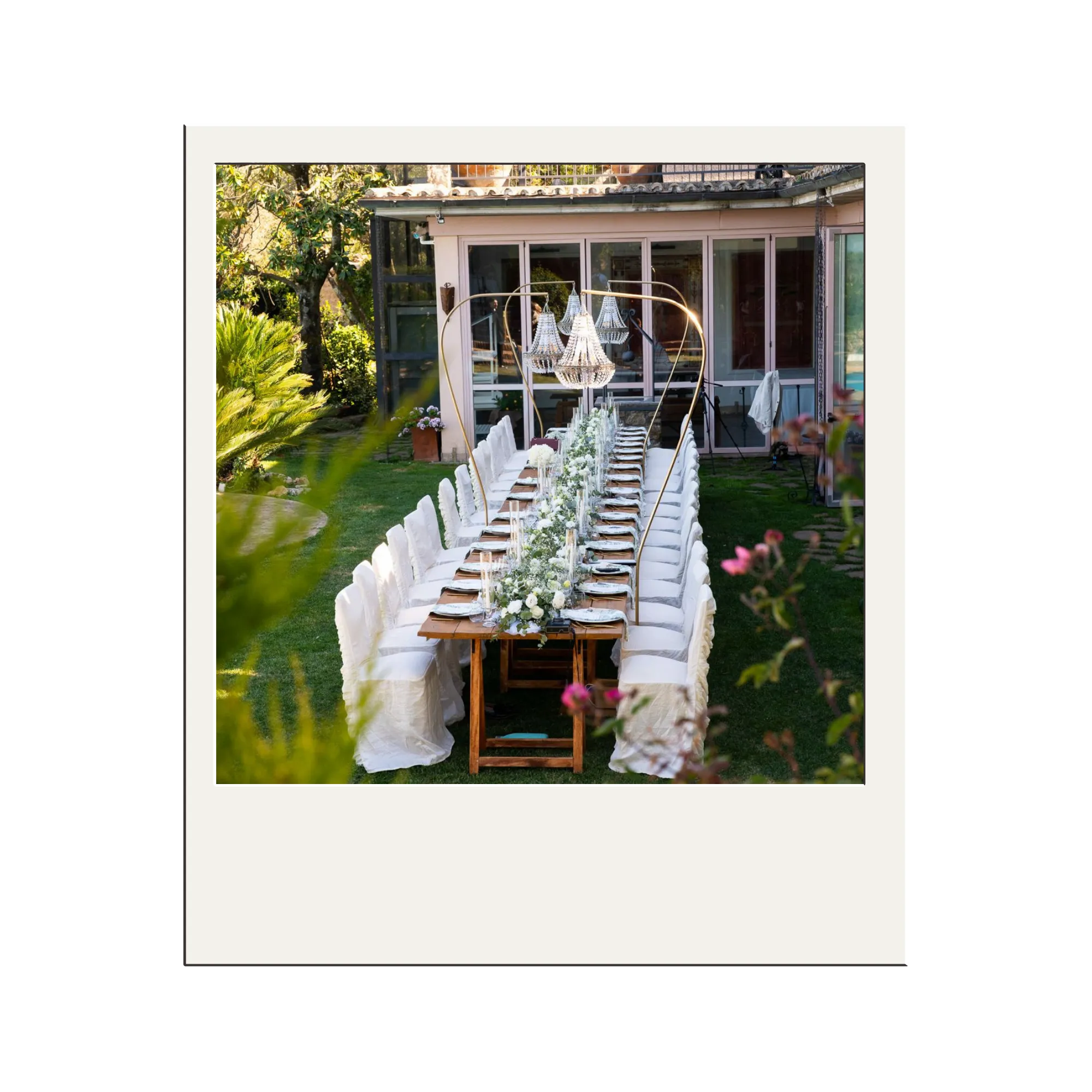 Outdoor evening event with round tables covered in yellow tablecloths, white chairs, string lights overhead, and guests mingling and seated.