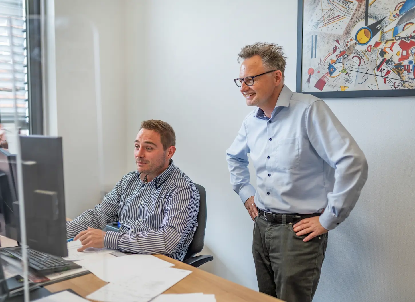 Zwei Mitarbeiter von Schoetz & Partner bei der gemeinsamen Arbeit am Bildschirm in der Kanzlei in Göppingen.