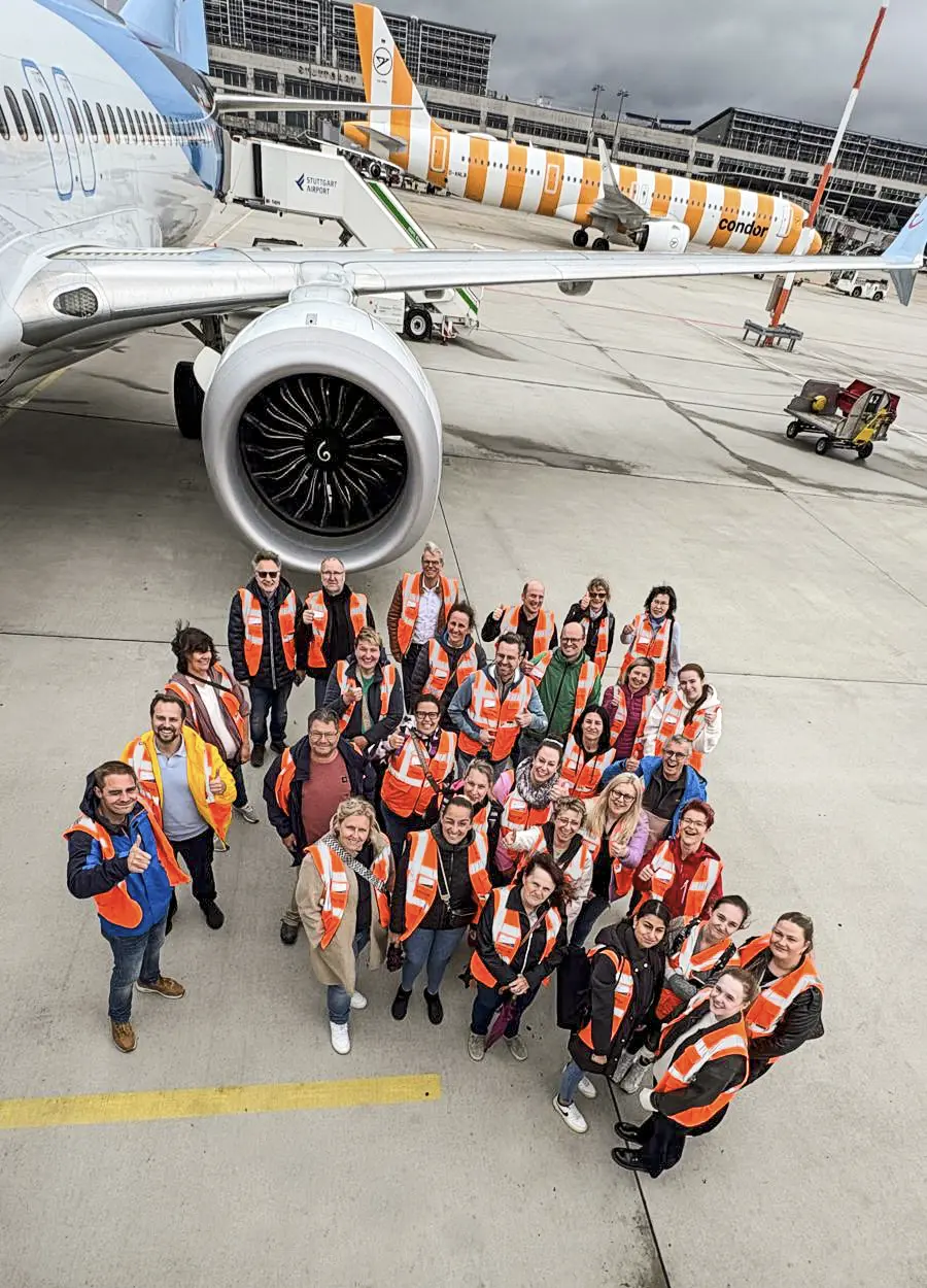 Team von Schoetz & Partner beim Betriebsausflug 2026 auf dem Vorfeld des Flughafens Stuttgart neben einem Flugzeug.