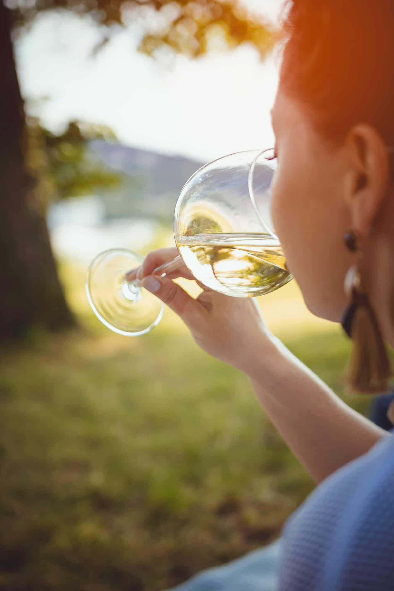 woman drinking wine outside by lake/pond