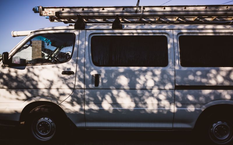 Tradie van with roof ladder parked in afternoon light