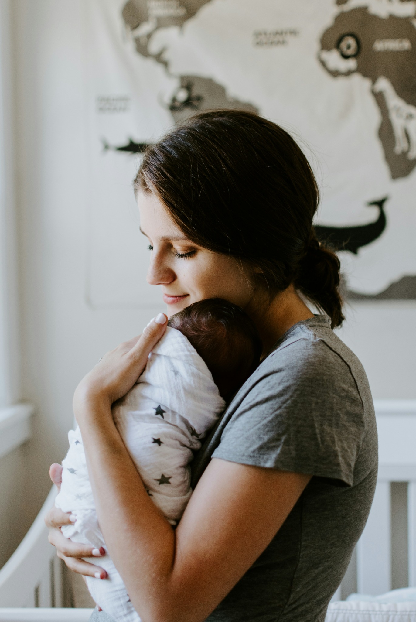 A mother holding her swaddled newborn close