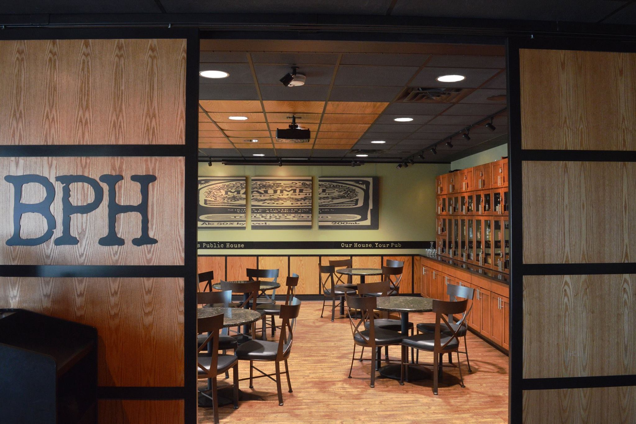 Warm atmospheric interior of upscale gastropub, cozy booth seating with amber pendant lights, dark wood bar in background, moody cinematic photography