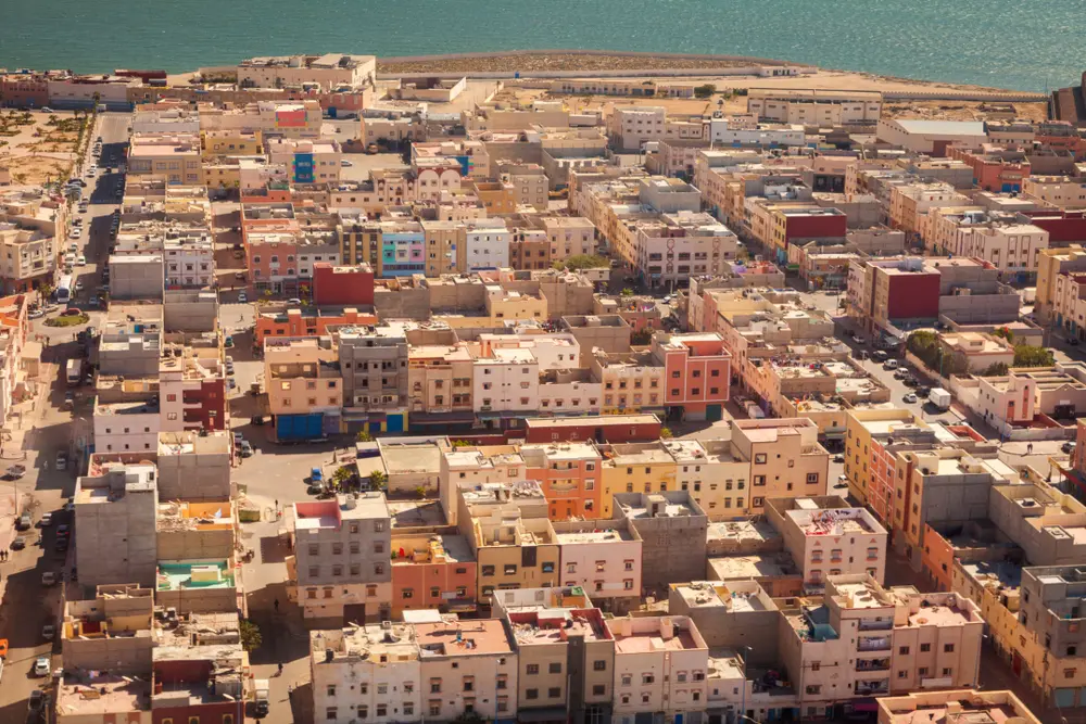 Aerial view of Dakhla city, with low-rise buildings, a palm-lined square and the Atlantic beyond