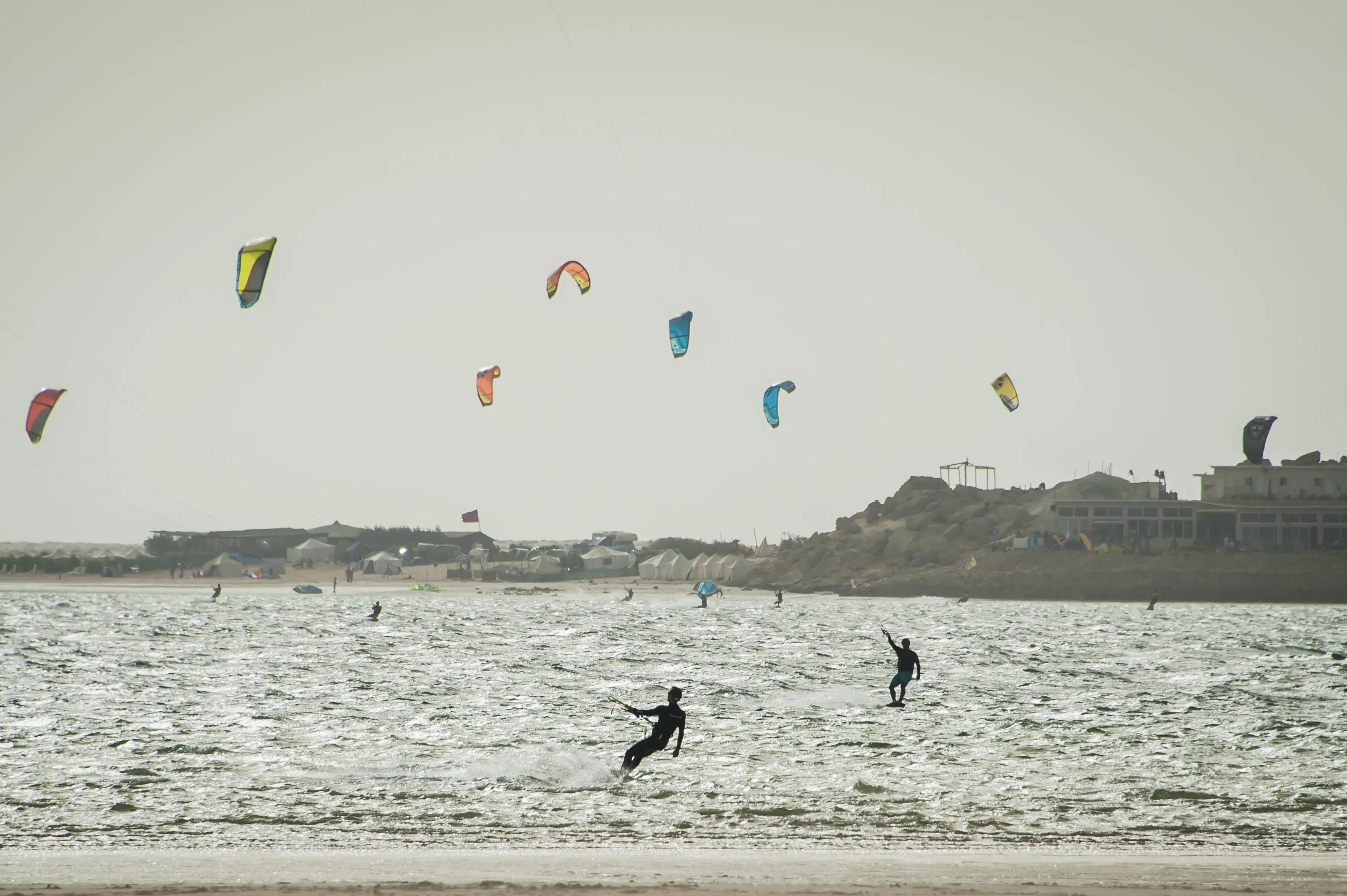 A wide view of the Dakhla lagoon with kitesurfers on the water and camps along the shoreline behind