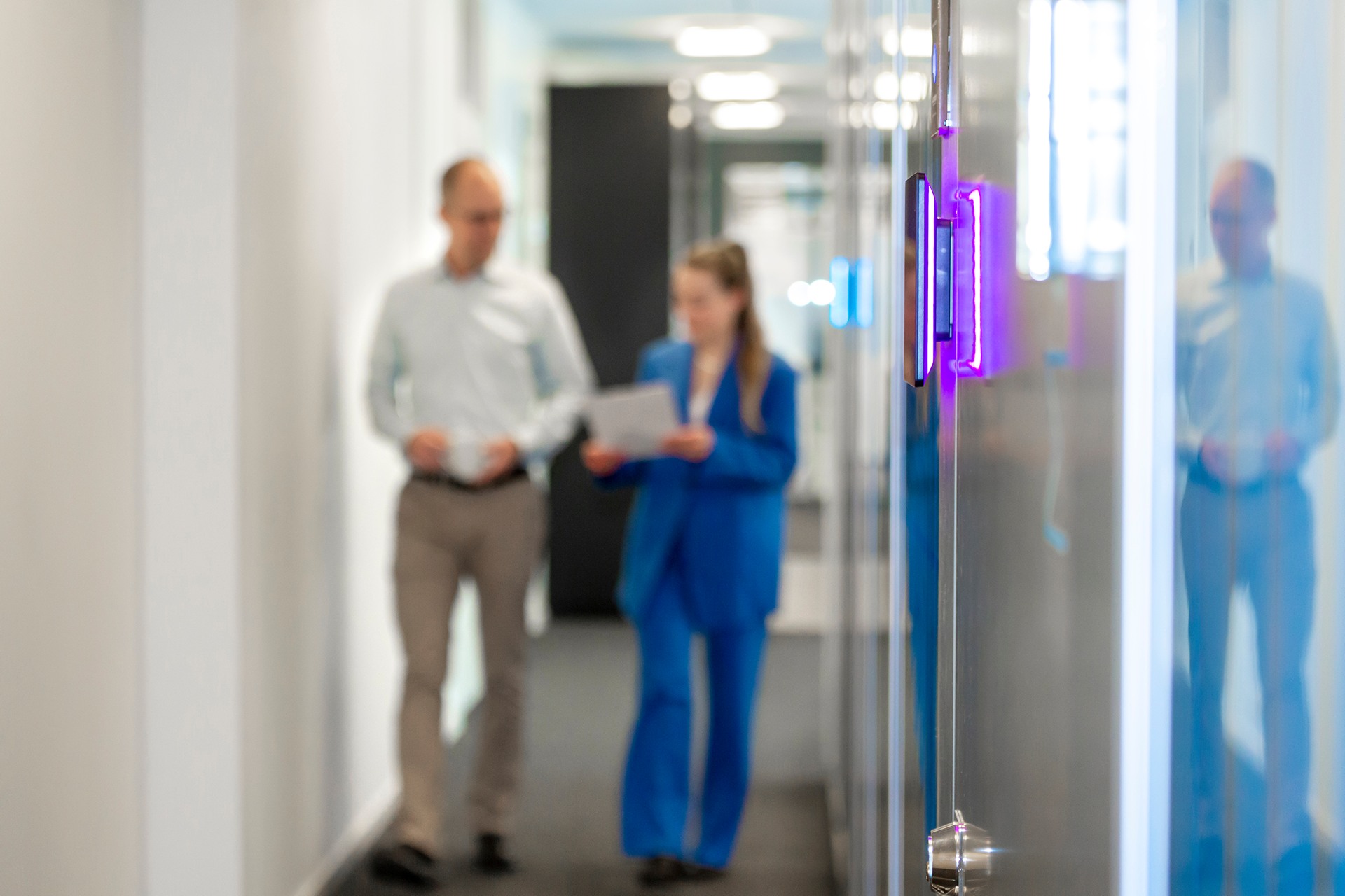 Two people walking in a corridor and talking.